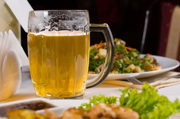 Glass Mug of Beer on Table Amongst Plates of Food on Table in Restaurant