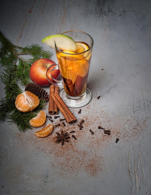 glass mug of hot mulled wine with spices on gray textured background