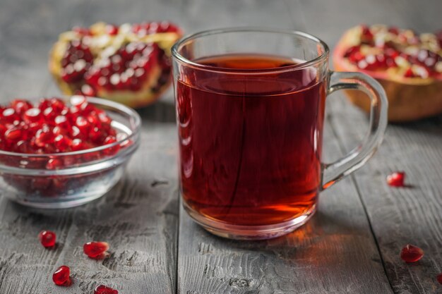 Glass mug with pomegranate juice and pomegranate seeds on a wooden table. Drink useful for health.