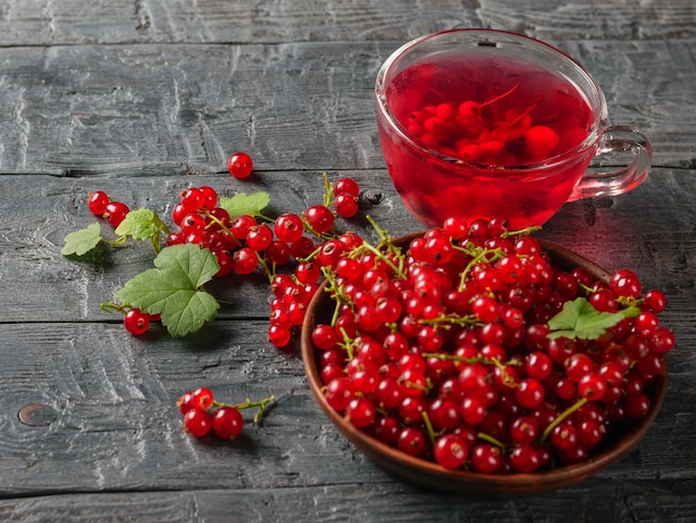 Glass mug with a refreshing drink of red currant and a bowl of fresh berries