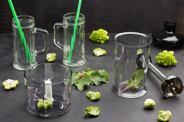 Glass mugs with broccoli leaves and green straws.