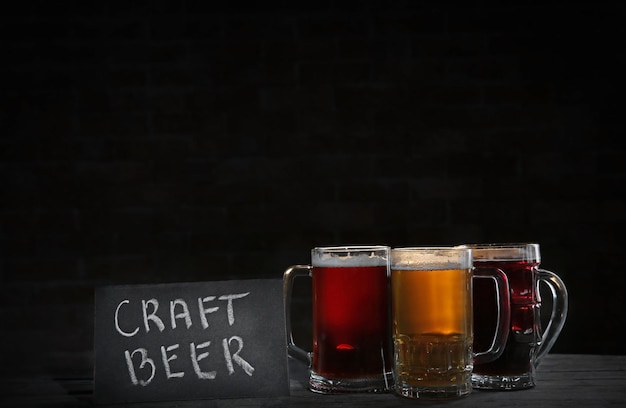 暗い背景にさまざまな種類のクラフトビールが入ったガラスのマグカップ