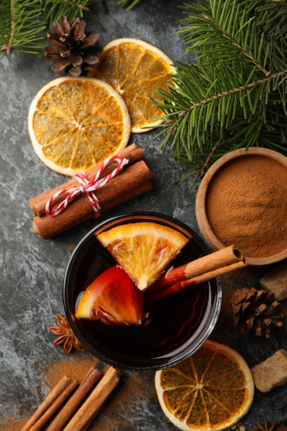 Glass of mulled wine and ingredients on black smokey background