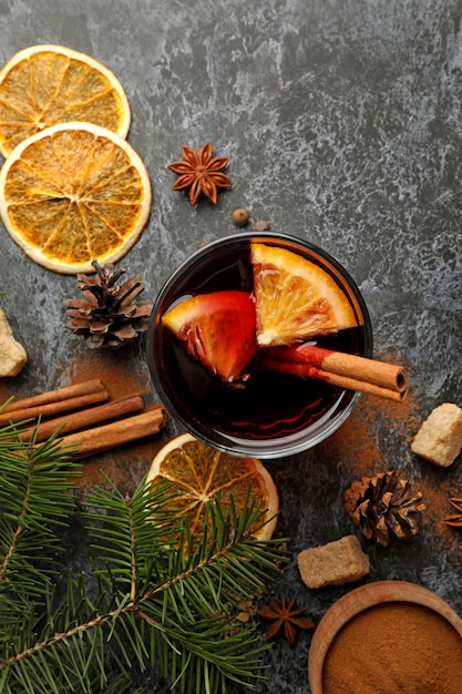 Glass of mulled wine and ingredients on black smokey