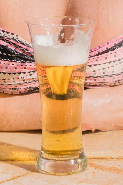 写真 ビキニを着た女性の前でビールを一杯