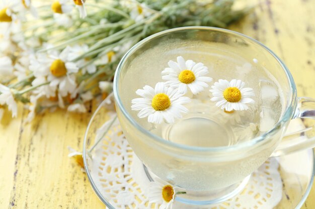 写真 木の色の背景に氷とカモミールの花を入れた冷たいカモミールティーのグラス