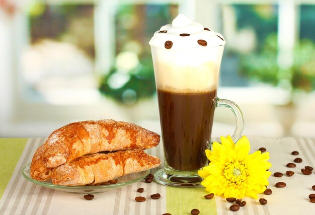 Фото Стакан свежего кофейного коктейля и блюдце с рогаликами на столе
