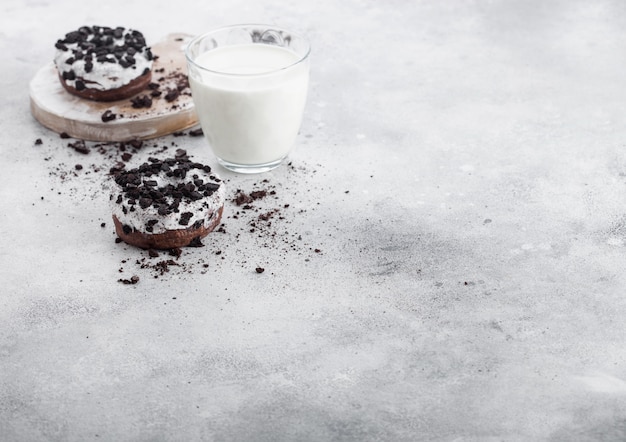 Фото Стакан молока и пончики с черным печеньем на каменный кухонный стол.