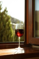 Бокал красного вина стоит на деревянном подоконнике