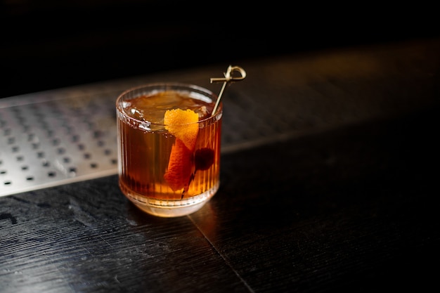 Glass of a Old Fashioned cocktail on the wooden steel bar counter