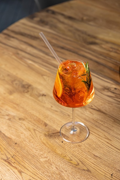 A glass of orange cocktail with a straw in it