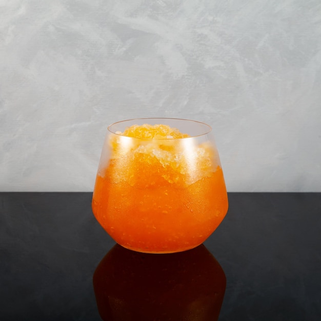 Photo glass of orange granizado or slushie drink refreshing iced fruit drink sweet citrus shaved ice