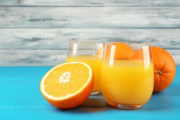 Glass of orange juice on color wooden background