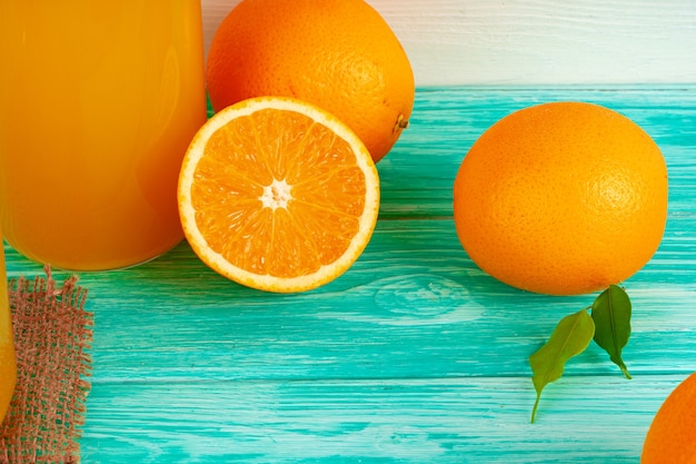 Glass of orange juice and cut oranges on table