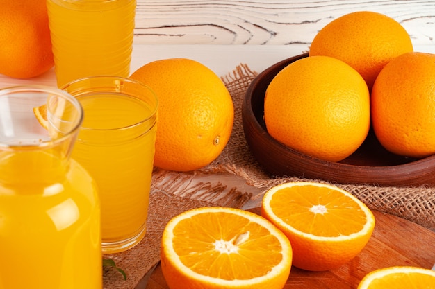 Glass of orange juice and cut oranges on table