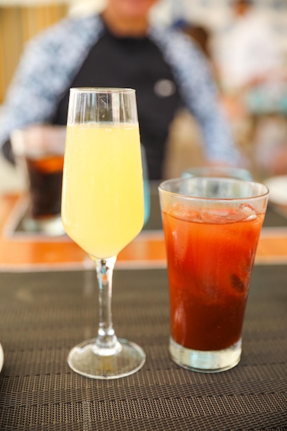 A glass of orange juice and a drink on a bar.