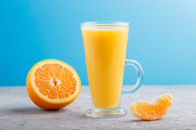 Photo glass of orange juice on gray and blue. side view