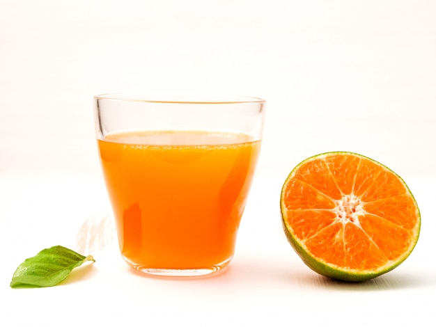 A glass of orange juice and half piece of orange.