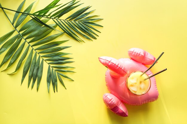 Glass of orange juice in inflatable pink flamingo