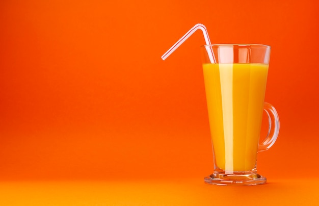 Glass of orange juice isolated on colour orange background with copy space for text