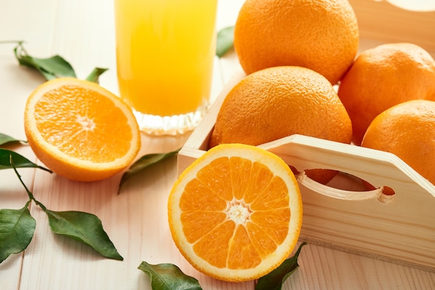 Glass of orange juice and orange fruits on wooden surface