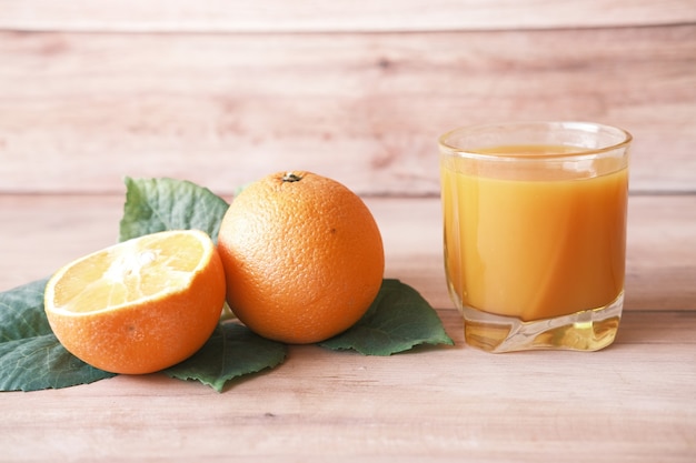 Glass of orange juice and orange on table