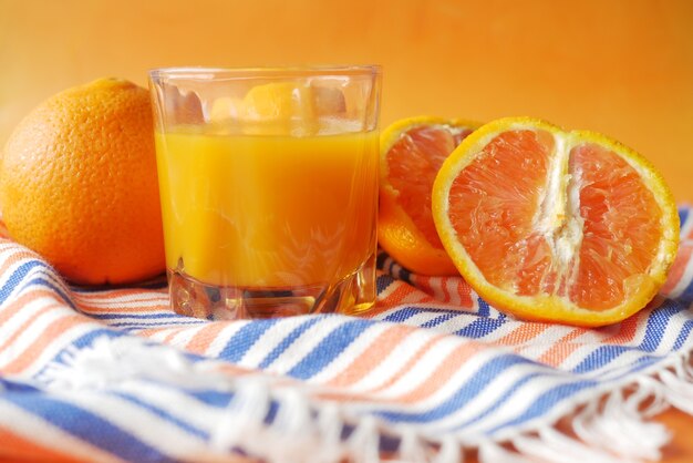테이블에 오렌지 주스 한 잔과 오렌지 한 조각