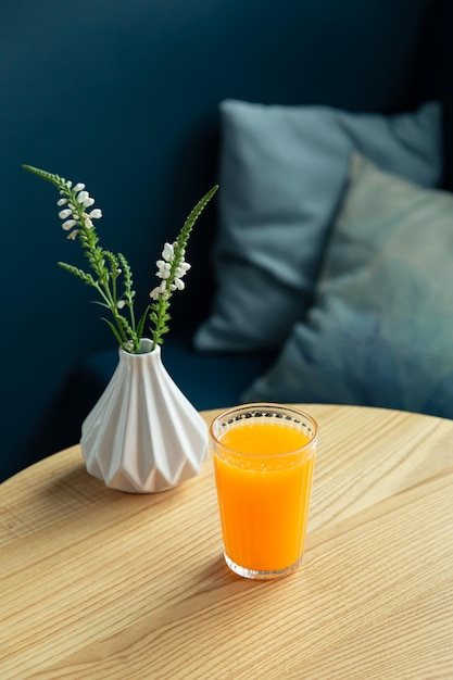 파란색 인테리어의 테이블에 있는 오렌지 주스 한 잔