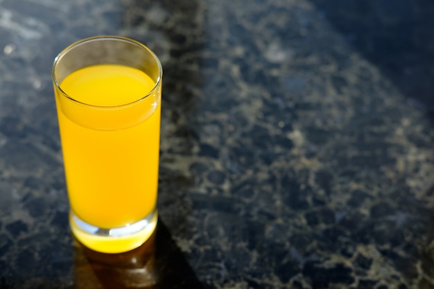 Glass of orange juice on table in kitchen