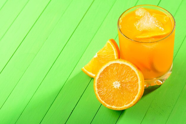 녹색 나무 테이블에 얼음과 오렌지 주스 한 잔