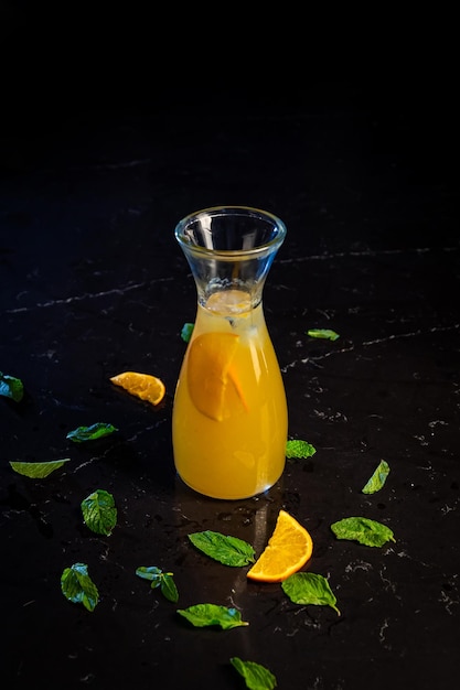 Стакан апельсинового сока с листьями на черном фоне