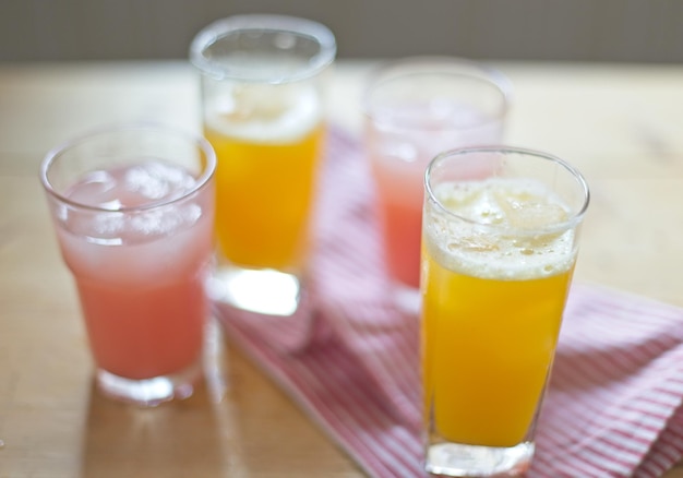 A glass of orange juice with a pink and white striped table cloth.