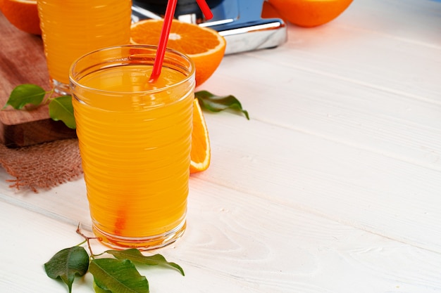 Glass of orange juice with red straw on table