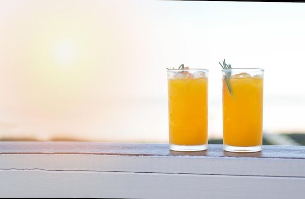 Glass of orange juice on wooden table fresh orange Juice with orange fruit and rosemary in the morning view nature background