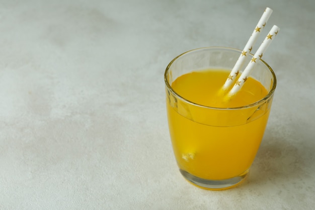 Glass of orange soda on white textured surface