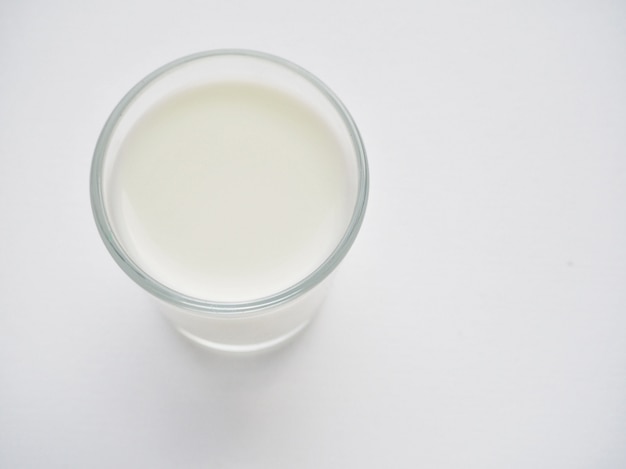 A glass of organic milk on a white surface.