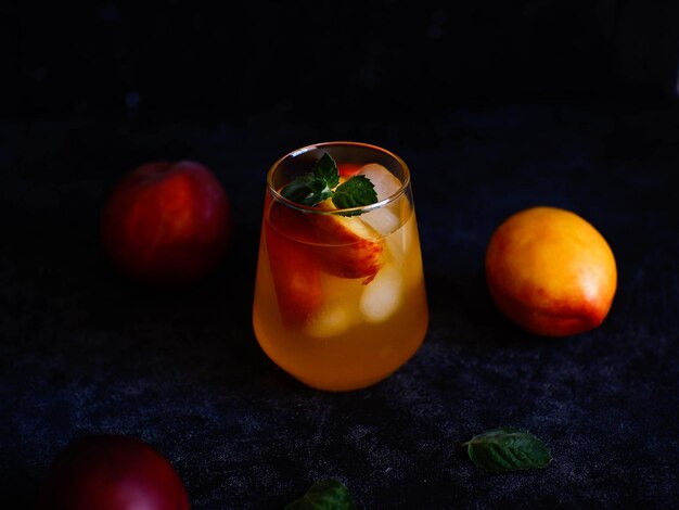 A glass of peach cocktail with ice mint leaves on a dark background Bar concept and summer drinks concept