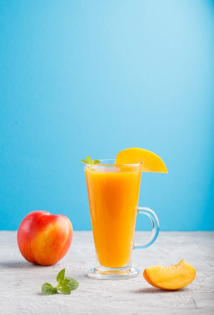 Glass of peach juice on a gray and blue background, Side view