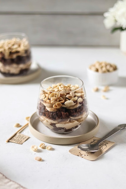 A glass of peanut butter and banana overnight oats with a spoon on a white table.