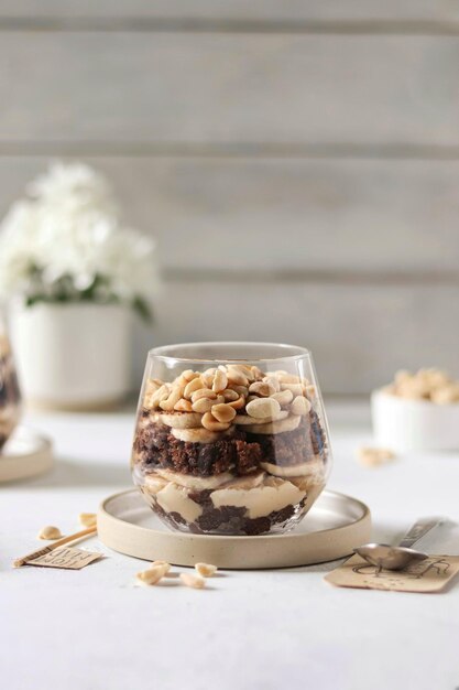 A glass of peanut butter and chocolate brownie trifle sits on a table.