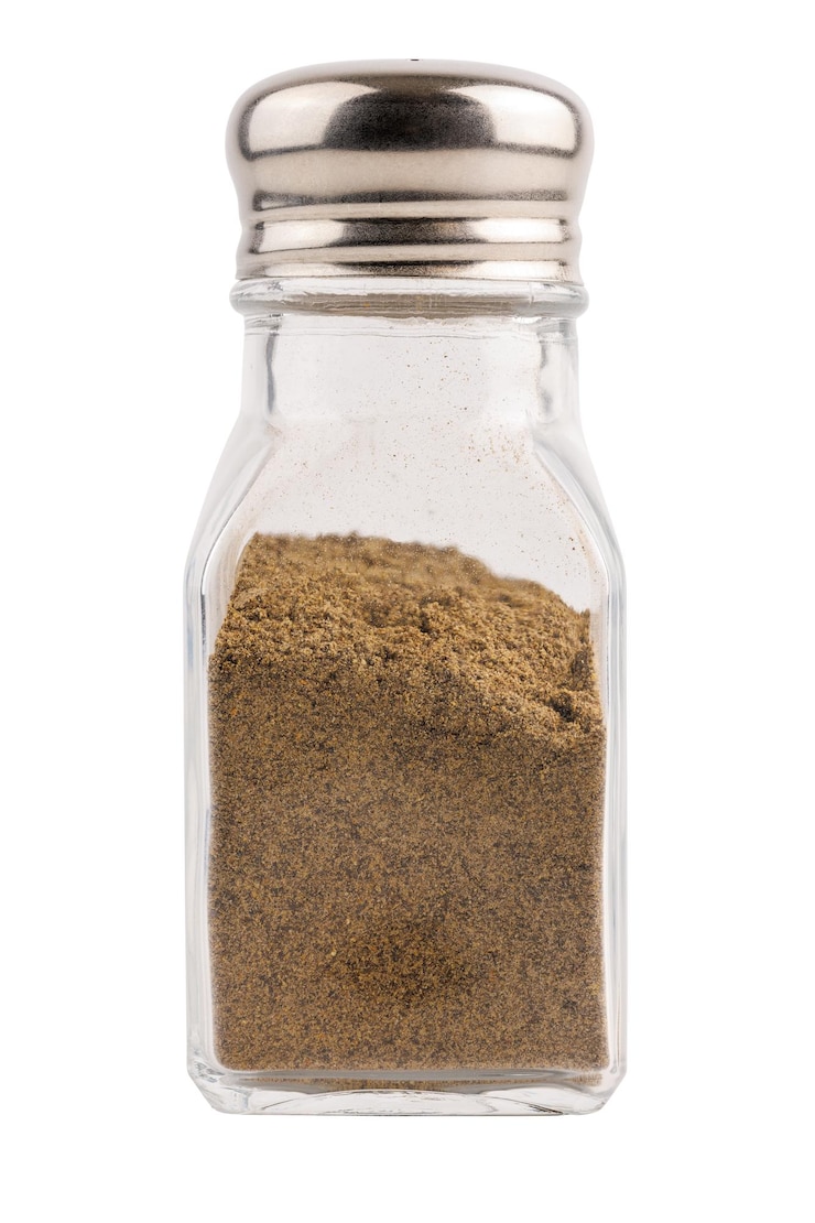 Photo glass pepper pot with ground black pepper isolated on white background