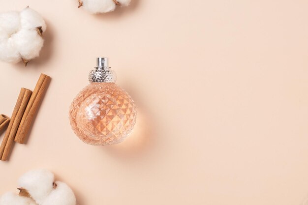 glass perfume bottle with cinnamon sticks and cotton flowers The concept of a spicy woody scent