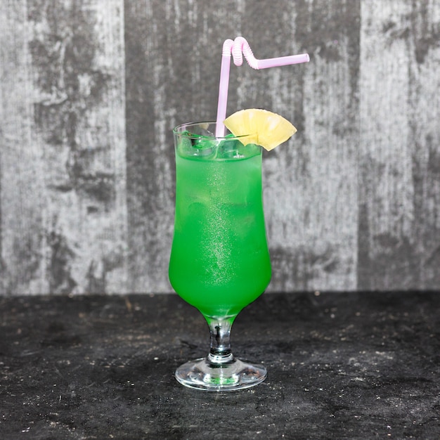 Glass of pineapple cocktail isolated on a gray background