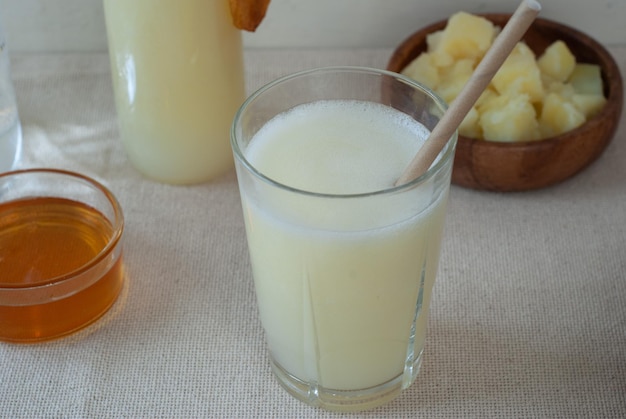 A glass of pineapple juice with a wooden spoon in it.