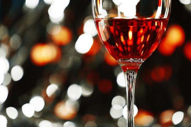 A glass of pink wine on blurred lighted background