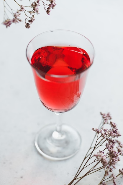 Glass of pink wine on a white table with flowers