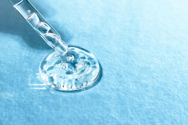 Glass pipette with acid for moisturizing the skin on a blue textural background closeup