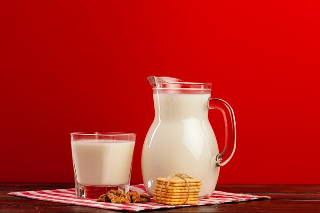 Brocca di vetro e tazza di latte con i biscotti