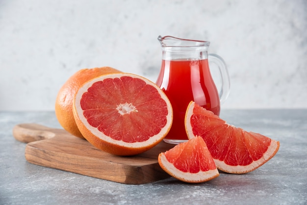 Glass pitcher of grapefruit juice with slices of fruits. 