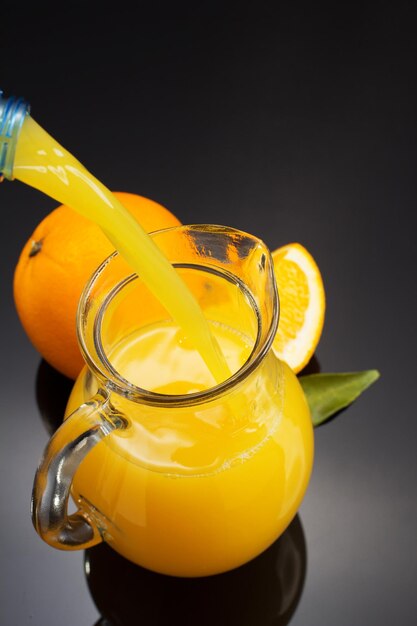 Glass pitcher and orange juice on black